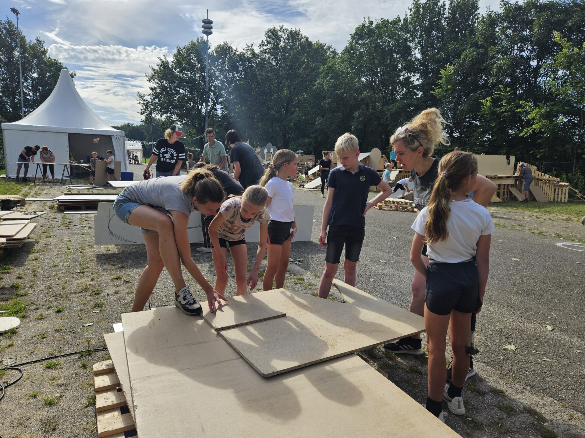Kinderen met begeleidster die rond om een grote platte plank staan